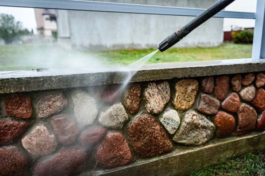 cleaning-dirty-stone-fence-using-high-pressure-power-washer